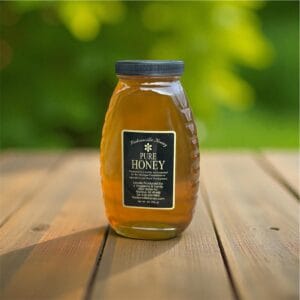 Jar of raw honey in classic glass queenline jar.